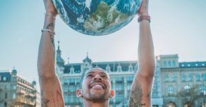 29-Nation Poll Shows a Huge Majority Are As Concerned About Climate Change As They Are With COVID-19 man holds up planet globe earth green sustainable pucdomain Peggy Anke
